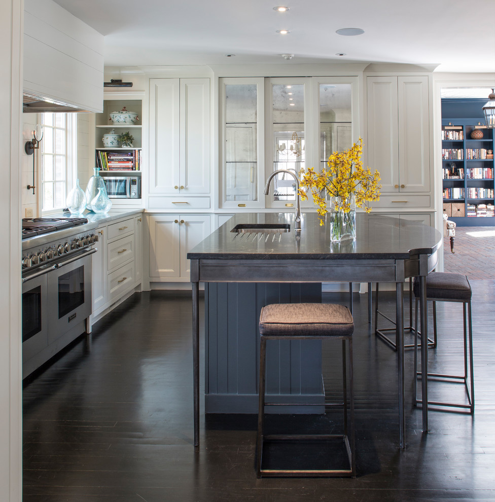Small transitional l-shaped dark wood floor and brown floor kitchen photo with an undermount sink, white cabinets, marble countertops, white backsplash, wood backsplash, stainless steel appliances, an island, black countertops and shaker cabinets
