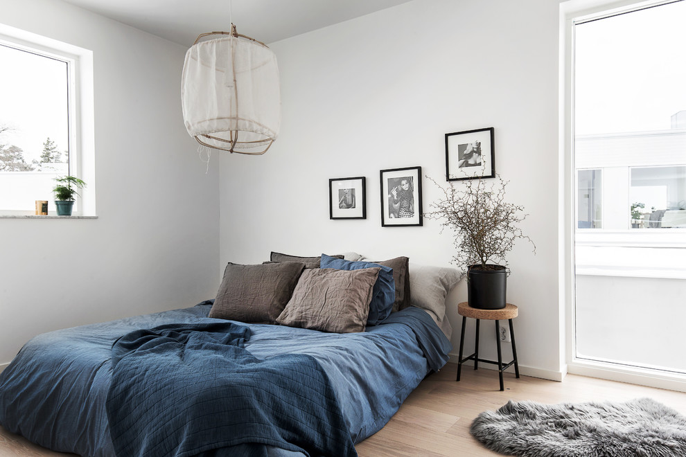Design ideas for a mid-sized scandinavian guest bedroom in Stockholm with white walls, light hardwood floors and no fireplace.