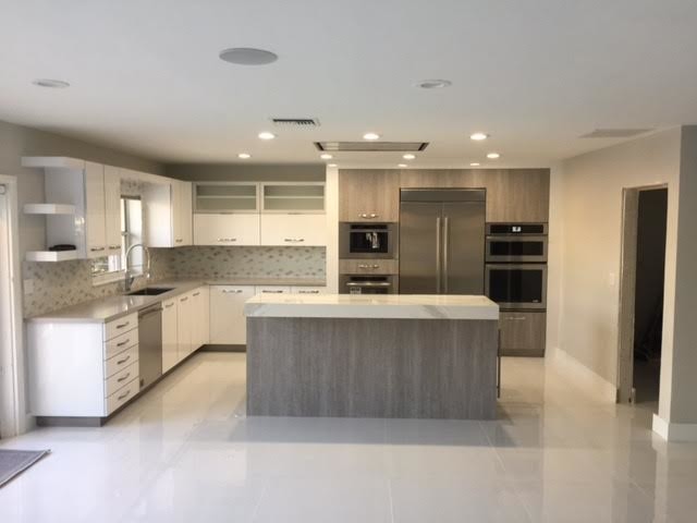 Mid-sized transitional l-shaped porcelain tile open concept kitchen photo in Miami with an undermount sink, flat-panel cabinets, white cabinets, marble countertops, gray backsplash, stainless steel appliances and an island