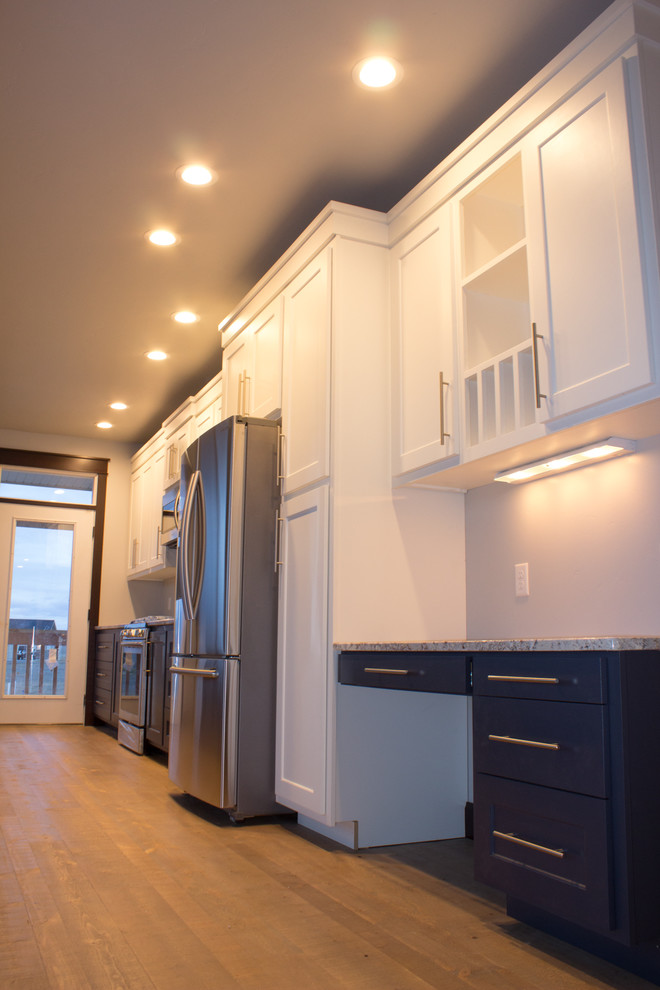 Mid-sized transitional single-wall medium tone wood floor and brown floor eat-in kitchen photo with an undermount sink, shaker cabinets, white cabinets, granite countertops, stainless steel appliances and an island
