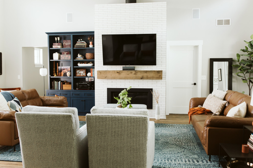 This is an example of a large country open plan living room in Grand Rapids with grey walls, vinyl flooring, a standard fireplace, a tiled fireplace surround, a wall mounted tv and brown floors.