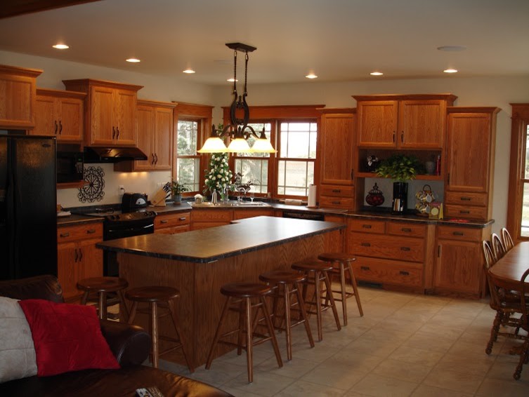 Mid-sized galley ceramic tile eat-in kitchen photo with a drop-in sink, flat-panel cabinets, light wood cabinets, laminate countertops, black appliances and an island