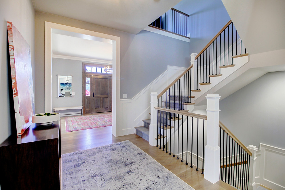 Expansive transitional wood u-shaped staircase in Denver with wood risers, mixed railing and decorative wall panelling.