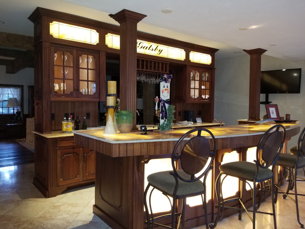 Aménagement d'un grand bar de salon avec évier parallèle classique en bois brun avec un placard avec porte à panneau surélevé, un plan de travail en onyx et un plan de travail jaune.