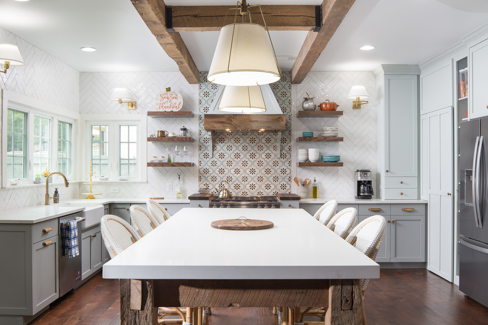 Photo of a beach style l-shaped kitchen in Atlanta with a farmhouse sink, shaker cabinets, grey cabinets, multi-coloured splashback, stainless steel appliances, dark hardwood floors, with island, brown floor and white benchtop.