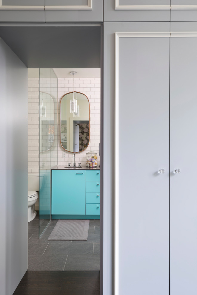 Inspiration for a large scandinavian master bathroom in New York with flat-panel cabinets, turquoise cabinets, an alcove tub, an alcove shower, a two-piece toilet, white tile, subway tile, white walls, ceramic floors, an undermount sink, solid surface benchtops, grey floor, a hinged shower door and black benchtops.