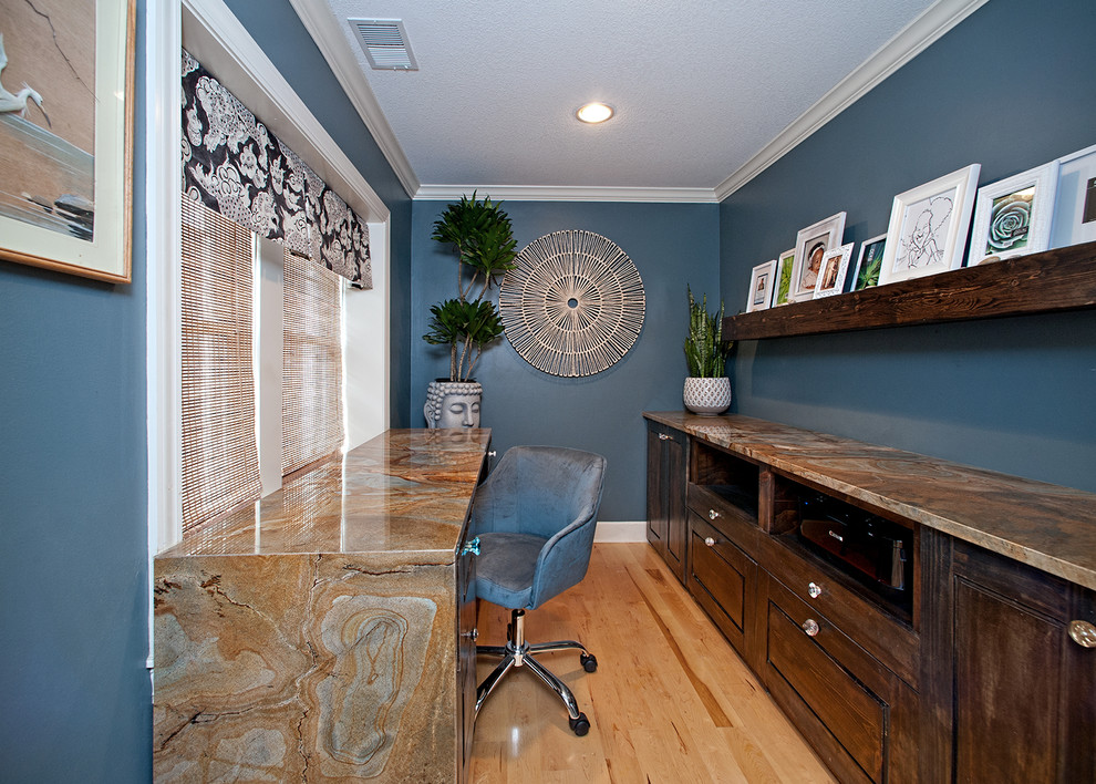 This is an example of a small eclectic study room in Kansas City with blue walls, light hardwood floors and a built-in desk.