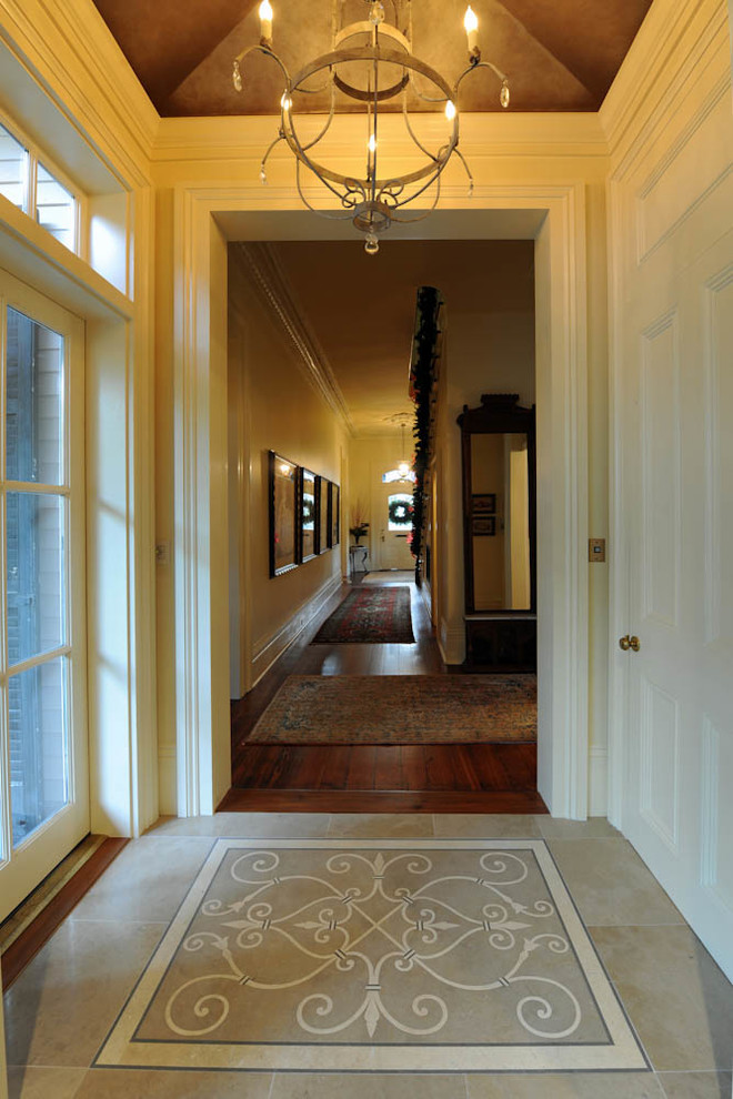 This is an example of a large traditional hallway in New Orleans with white walls and porcelain floors.