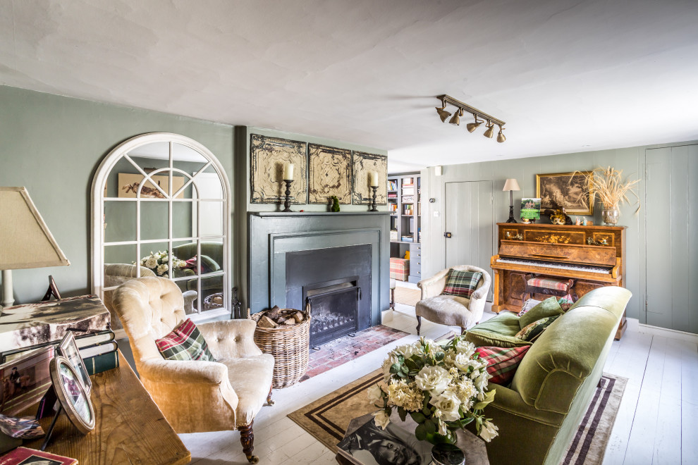 Country living room in Sussex with grey walls, painted wood flooring, a standard fireplace and white floors.