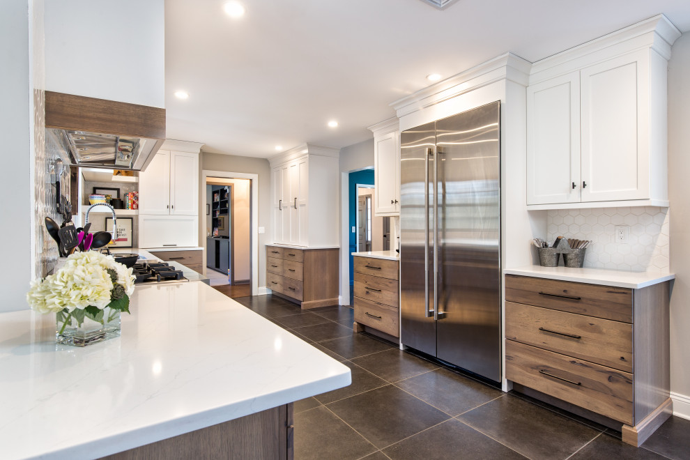 Photo of a mid-sized transitional u-shaped open plan kitchen in New York with an undermount sink, shaker cabinets, medium wood cabinets, quartz benchtops, white splashback, ceramic splashback, stainless steel appliances, ceramic floors, with island, grey floor and white benchtop.