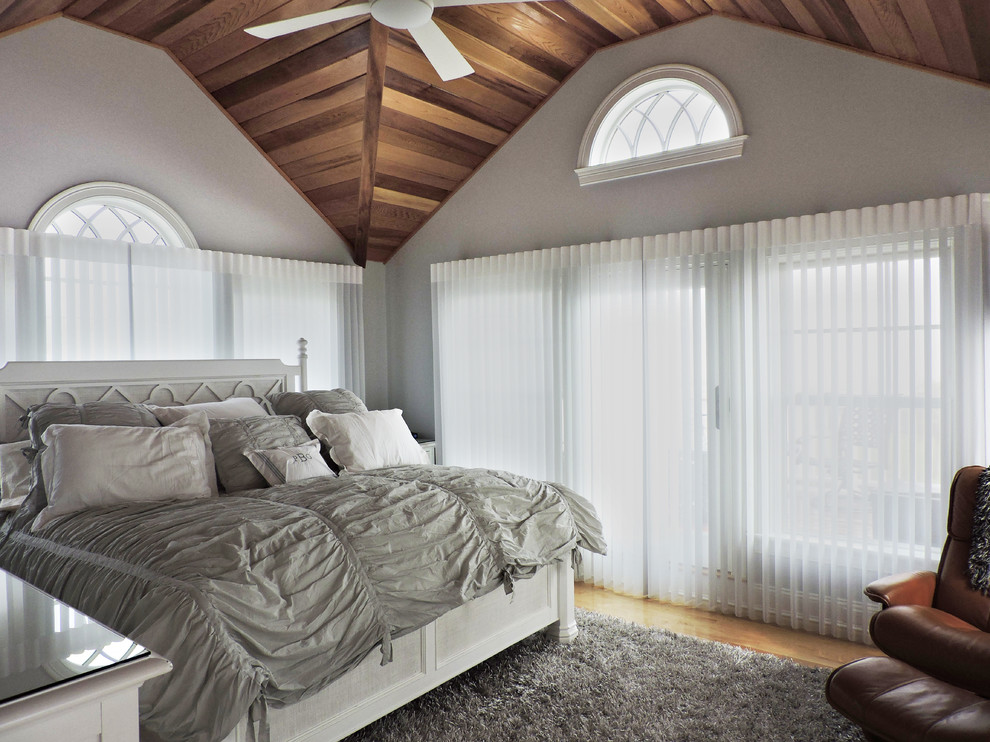 Example of a large beach style master light wood floor and beige floor bedroom design with gray walls and no fireplace