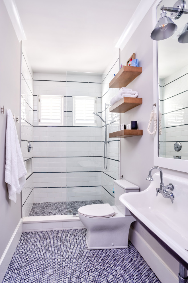 Mid-sized beach style 3/4 bathroom in Wilmington with an alcove shower, a one-piece toilet, white tile, subway tile, white walls, pebble tile floors, a wall-mount sink, blue floor, a hinged shower door, a double vanity and a floating vanity.