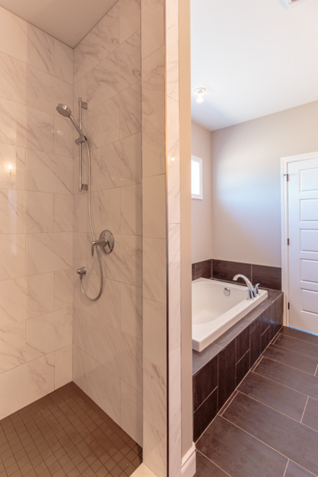 Photo of a large traditional master bathroom in Toronto with shaker cabinets, a drop-in tub, an open shower, a one-piece toilet, brown tile, porcelain tile, beige walls, porcelain floors, an undermount sink, granite benchtops and brown cabinets.