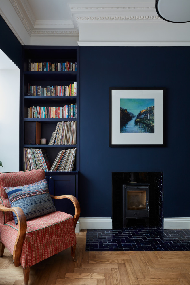 На фото: гостиная комната среднего размера в стиле фьюжн с синими стенами, светлым паркетным полом, печью-буржуйкой, фасадом камина из плитки и бежевым полом с