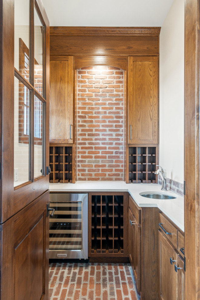 This is an example of a small country wine cellar in Dallas with brick floors, display racks and red floor.