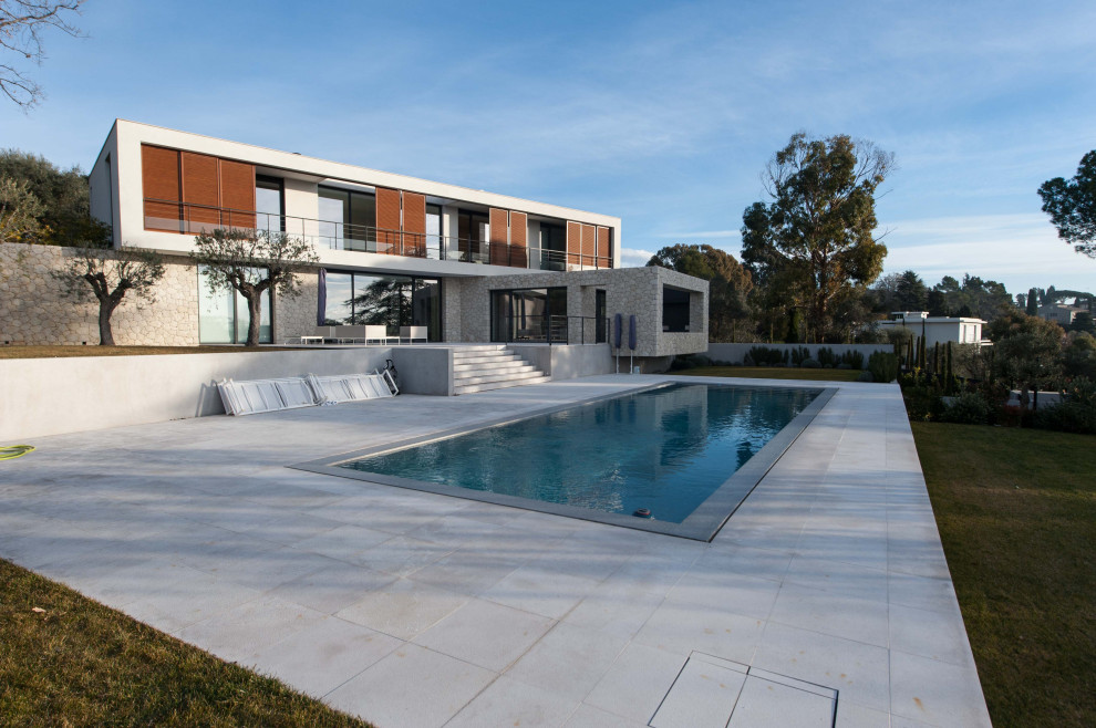 Immagine di una piscina a sfioro infinito design rettangolare di medie dimensioni e davanti casa con pavimentazioni in pietra naturale