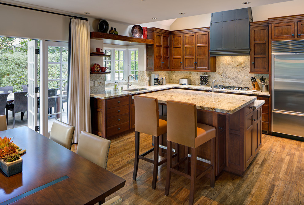 This is an example of a large transitional l-shaped eat-in kitchen in Other with an undermount sink, raised-panel cabinets, medium wood cabinets, granite benchtops, stone slab splashback, stainless steel appliances, medium hardwood floors, with island and beige benchtop.