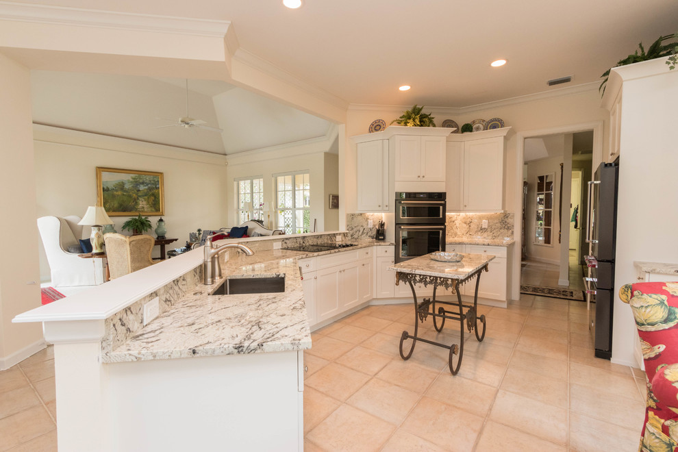 Inspiration for a large transitional porcelain tile eat-in kitchen remodel in Miami with an undermount sink, shaker cabinets, white cabinets, granite countertops, gray backsplash, stone slab backsplash, black appliances and an island