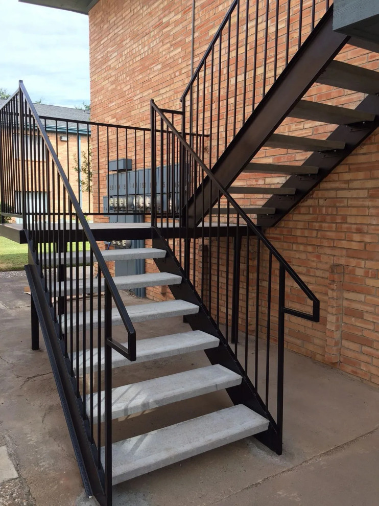 Пример оригинального дизайна: большая п-образная бетонная лестница в классическом стиле с бетонными ступенями, металлическими перилами и кирпичными стенами