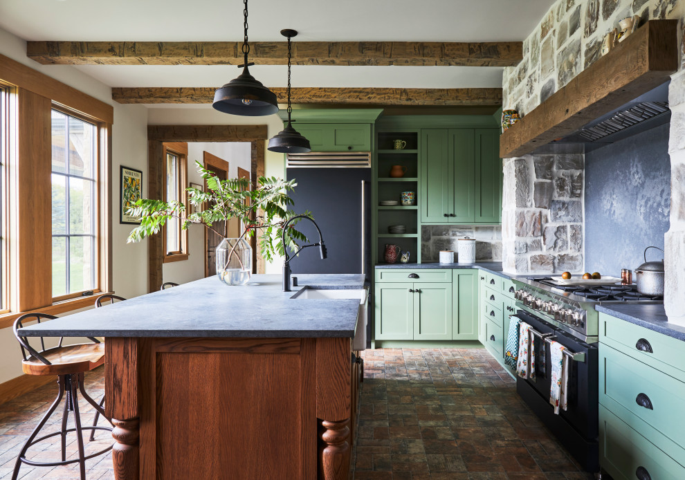 This is an example of a mid-sized country l-shaped separate kitchen in Milwaukee with a farmhouse sink, shaker cabinets, green cabinets, quartz benchtops, grey splashback, engineered quartz splashback, black appliances, brick floors, with island, brown floor, grey benchtop and exposed beam.