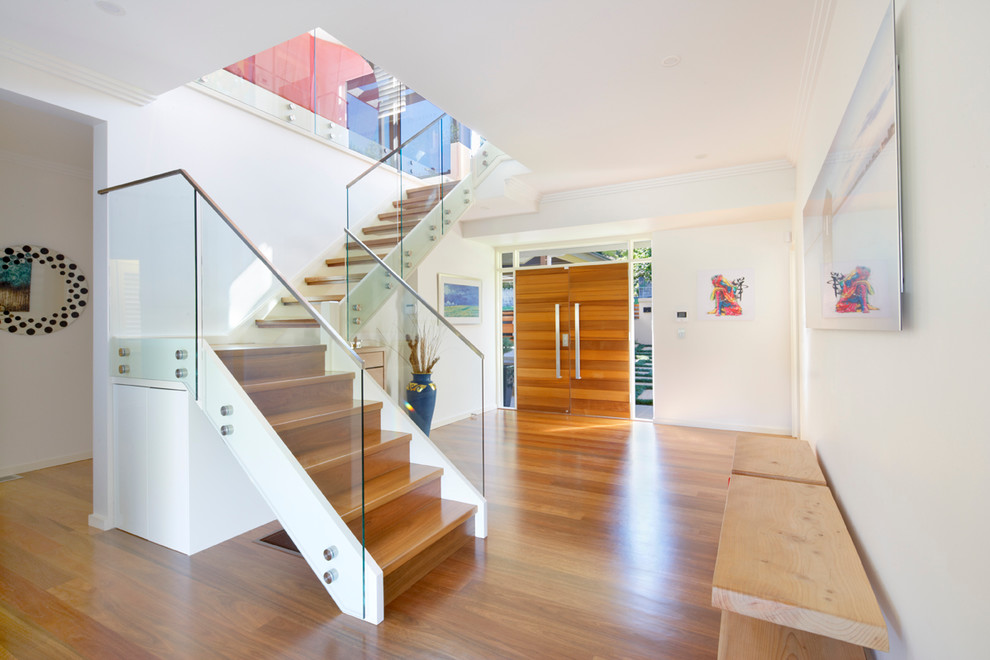 Photo of a mid-sized contemporary wood l-shaped staircase in Sydney with wood risers and glass railing.