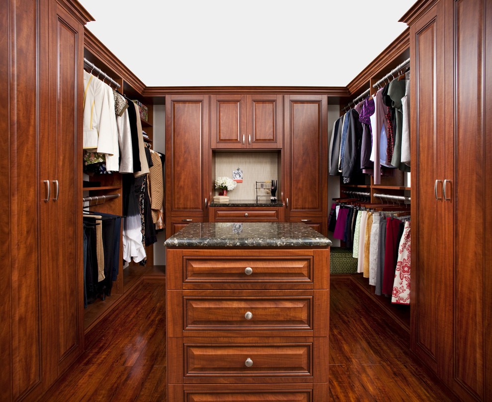 This is an example of a traditional walk-in wardrobe in Philadelphia with raised-panel cabinets and dark wood cabinets.