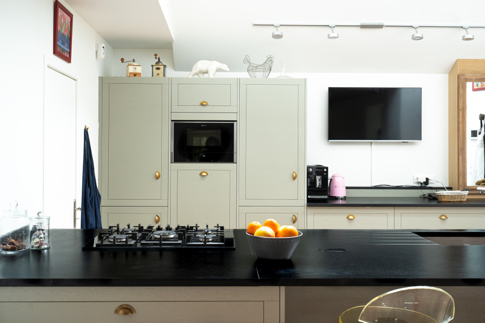 Photo of an expansive midcentury galley open plan kitchen in Other with an integrated sink, flat-panel cabinets, green cabinets, granite benchtops, black splashback, granite splashback, panelled appliances, cement tiles, with island, pink floor and black benchtop.