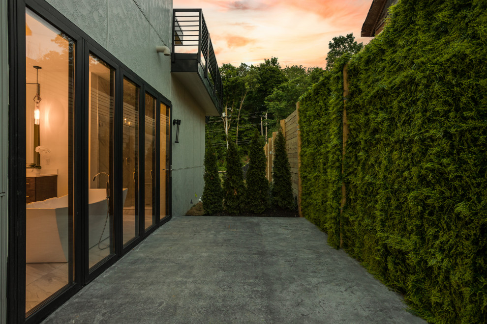 Cette image montre une terrasse latérale minimaliste de taille moyenne avec du béton estampé et aucune couverture.