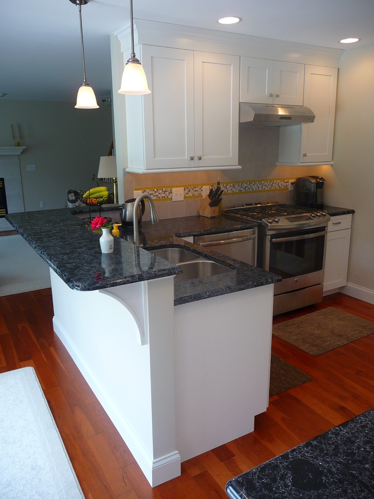 Mid-sized transitional l-shaped medium tone wood floor eat-in kitchen photo with a double-bowl sink, recessed-panel cabinets, white cabinets, quartz countertops, multicolored backsplash, ceramic backsplash, stainless steel appliances and a peninsula