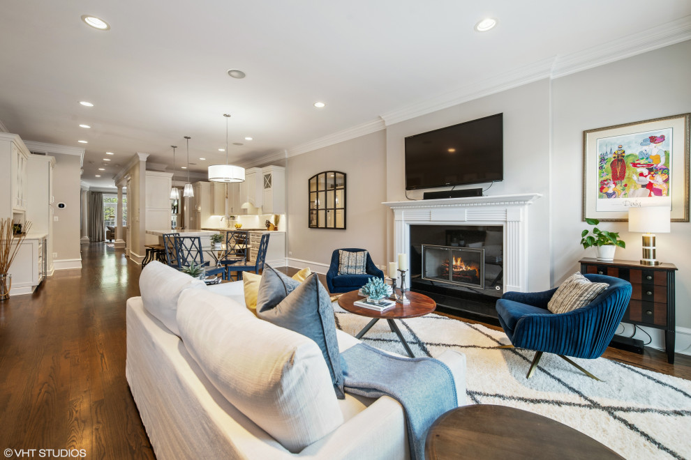 This is an example of a large traditional open plan living room in Chicago with grey walls, a standard fireplace, a wooden fireplace surround and brown floors.