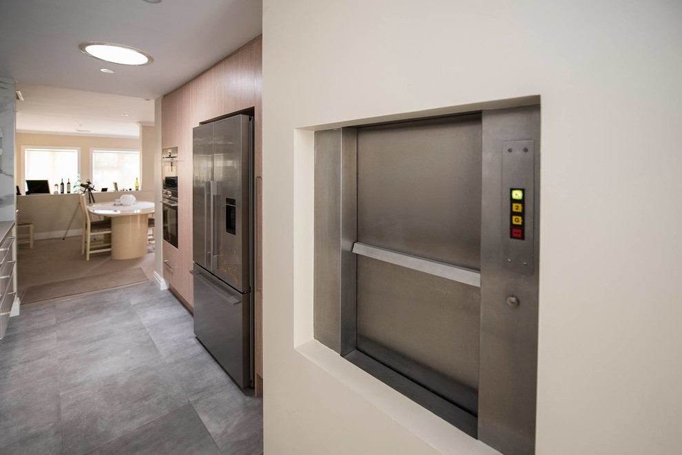 Mid-sized contemporary galley kitchen in Sydney with a double-bowl sink, flat-panel cabinets, white cabinets, quartz benchtops, white splashback, ceramic splashback, stainless steel appliances, porcelain floors, no island, grey floor and beige benchtop.