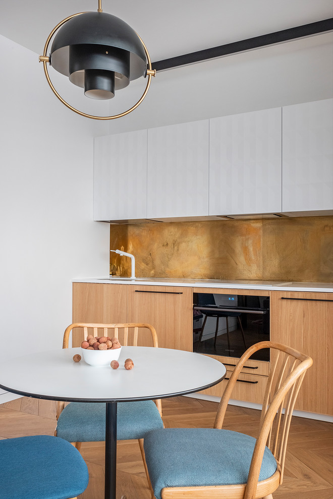 Inspiration for a small contemporary single-wall eat-in kitchen in Moscow with an undermount sink, flat-panel cabinets, light wood cabinets, quartzite benchtops, beige splashback, black appliances, medium hardwood floors, beige floor and white benchtop.