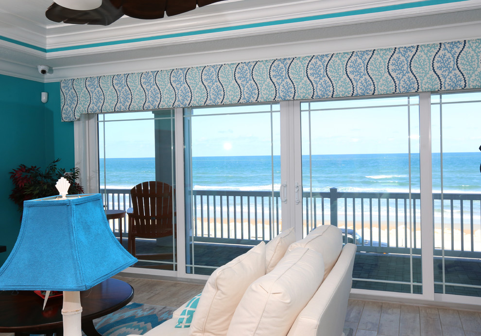 Design ideas for a mid-sized beach style enclosed family room in Orlando with blue walls, porcelain floors, a wall-mounted tv, beige floor and no fireplace.