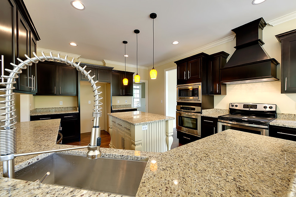 Eat-in kitchen - transitional u-shaped medium tone wood floor eat-in kitchen idea with an undermount sink, recessed-panel cabinets, dark wood cabinets, granite countertops and an island
