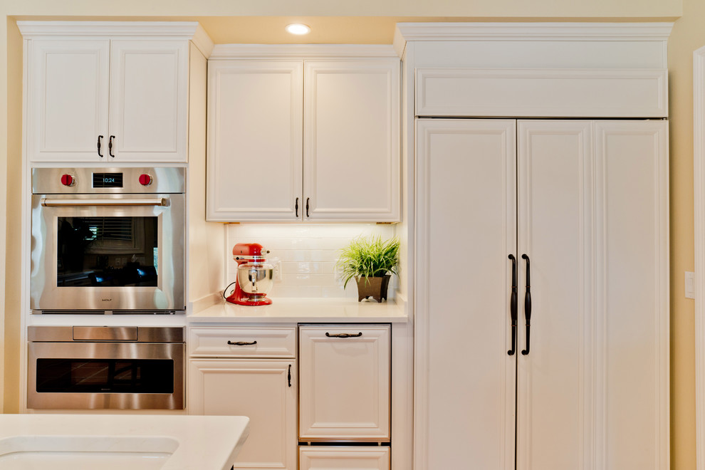 Large transitional u-shaped terra-cotta tile and orange floor eat-in kitchen photo with an undermount sink, recessed-panel cabinets, white cabinets, quartz countertops, white backsplash, subway tile backsplash, stainless steel appliances and an island