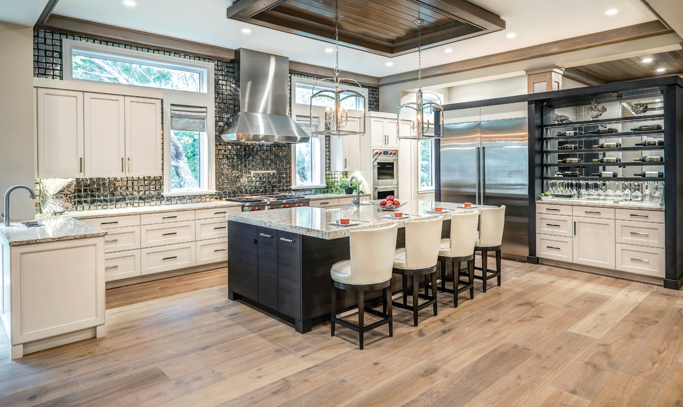 This is an example of a transitional u-shaped eat-in kitchen in Miami with a farmhouse sink, recessed-panel cabinets, granite benchtops, glass tile splashback, stainless steel appliances, light hardwood floors and with island.