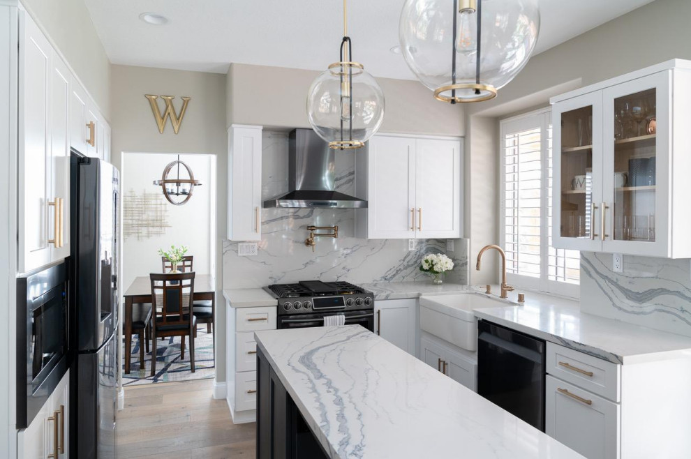 Mid-sized transitional l-shaped separate kitchen in Atlanta with a farmhouse sink, recessed-panel cabinets, white cabinets, white splashback, engineered quartz splashback, stainless steel appliances, medium hardwood floors, with island, brown floor, white benchtop and marble benchtops.