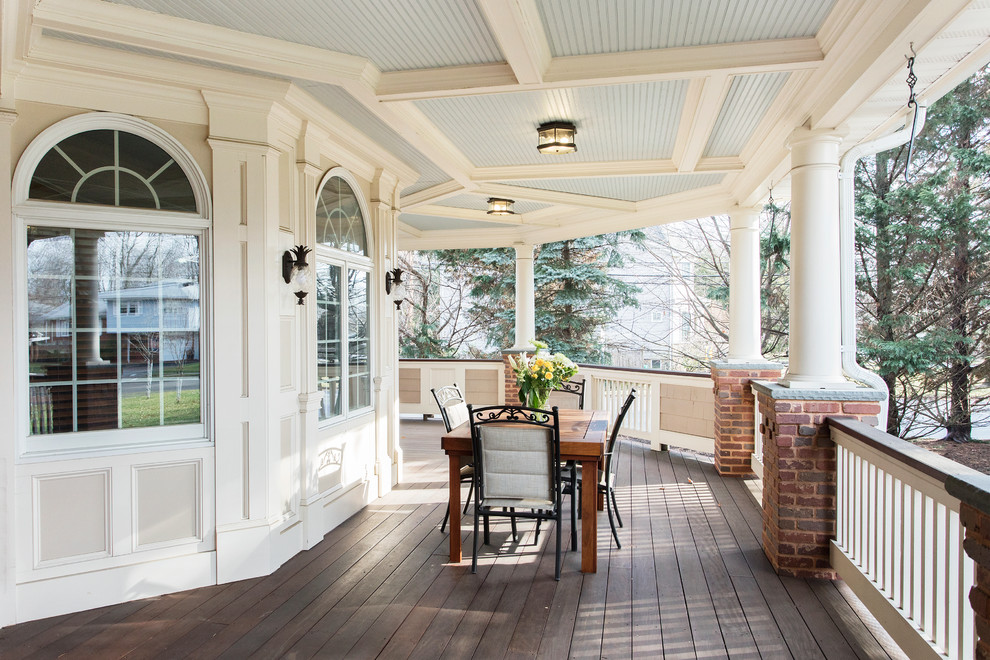 This is an example of a huge traditional front porch design in New York with a roof extension and decking.