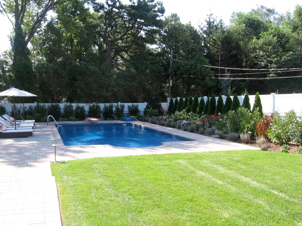 Photo of a mid-sized traditional backyard rectangular natural pool in New York with concrete pavers.
