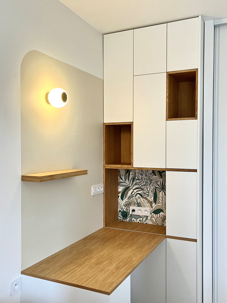 Modelo de despacho minimalista con paredes beige, suelo de madera clara, escritorio empotrado y papel pintado