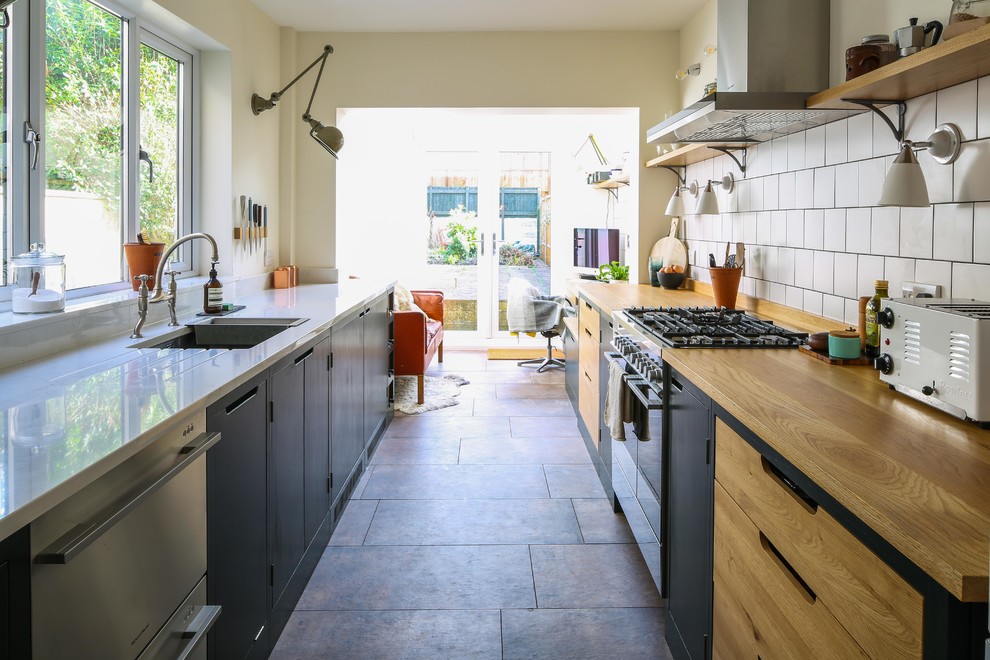 Mid-sized contemporary galley separate kitchen in Other with flat-panel cabinets, green cabinets, wood benchtops, white splashback, subway tile splashback, stainless steel appliances, no island, multi-coloured floor and a single-bowl sink.