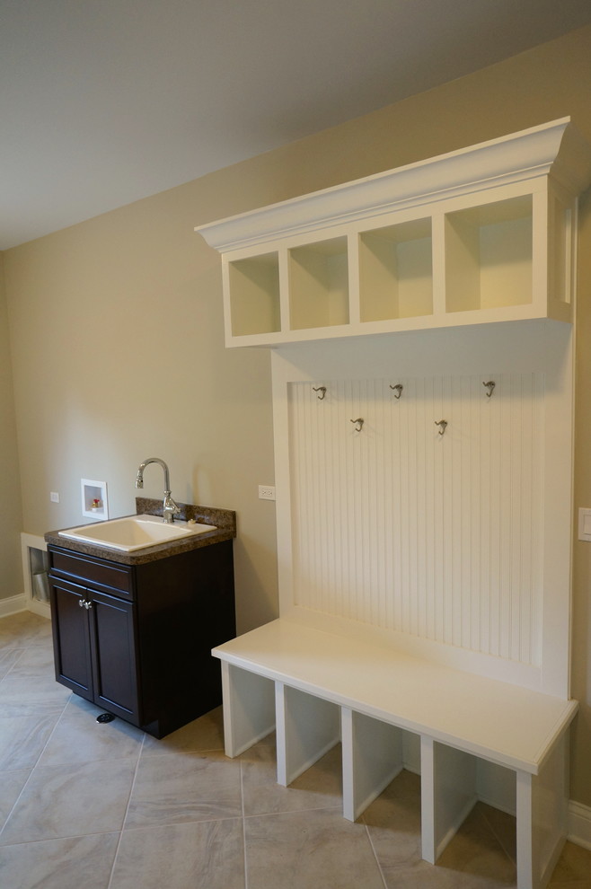 Photo of a mid-sized traditional utility room in Chicago with a drop-in sink, white cabinets, granite benchtops, beige walls, ceramic floors and a side-by-side washer and dryer.
