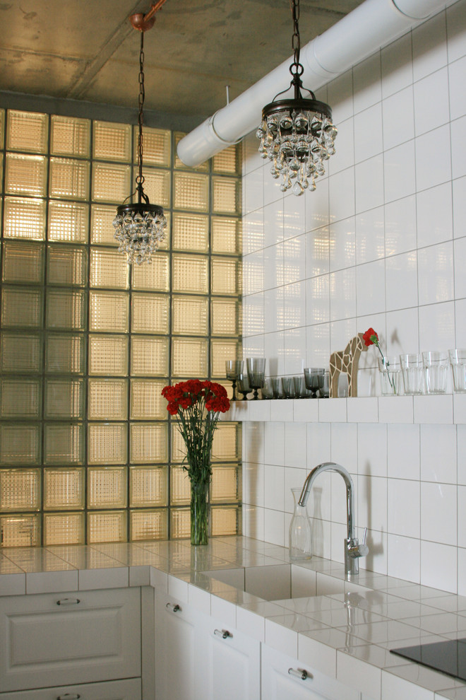Industrial kitchen in Moscow with an integrated sink, white cabinets, tile benchtops and white splashback.