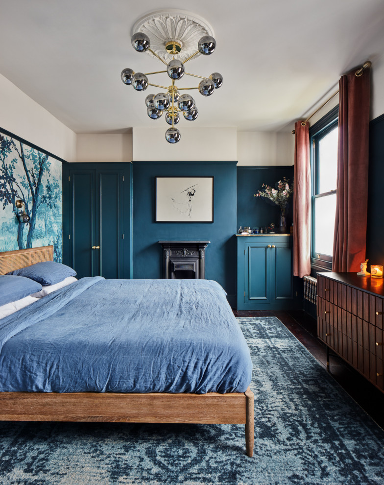 Modelo de dormitorio principal con paredes azules, suelo de madera oscura, todas las chimeneas y marco de chimenea de metal