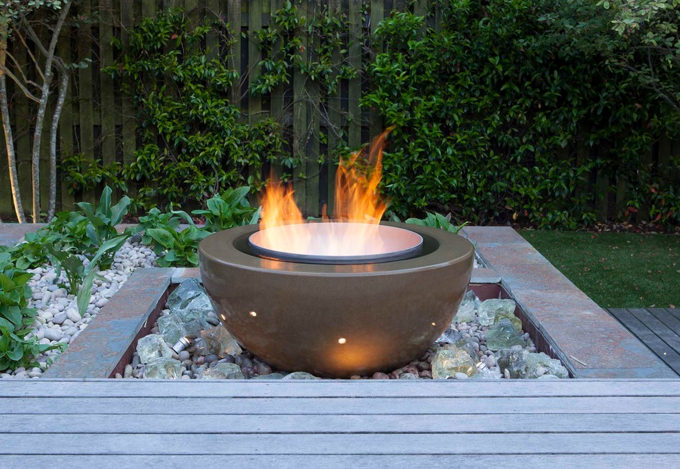 This is an example of a contemporary garden in London with a fire feature and decking.