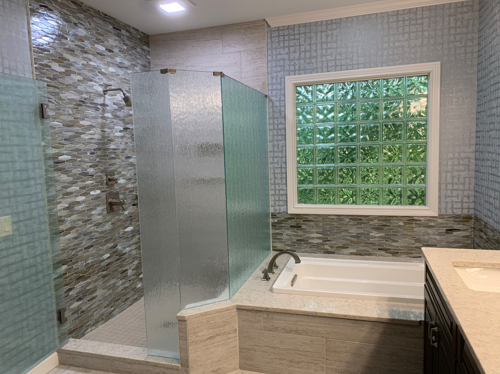 Drop-in bathtub - mid-sized transitional master multicolored tile and glass tile beige floor, double-sink and wallpaper drop-in bathtub idea in Cincinnati with raised-panel cabinets, dark wood cabinets, a two-piece toilet, multicolored walls, an undermount sink, quartz countertops, beige countertops, a niche and a built-in vanity