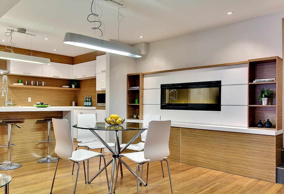 This is an example of a mid-sized modern kitchen/dining combo in Montreal with beige walls, bamboo floors, a hanging fireplace and a wood fireplace surround.
