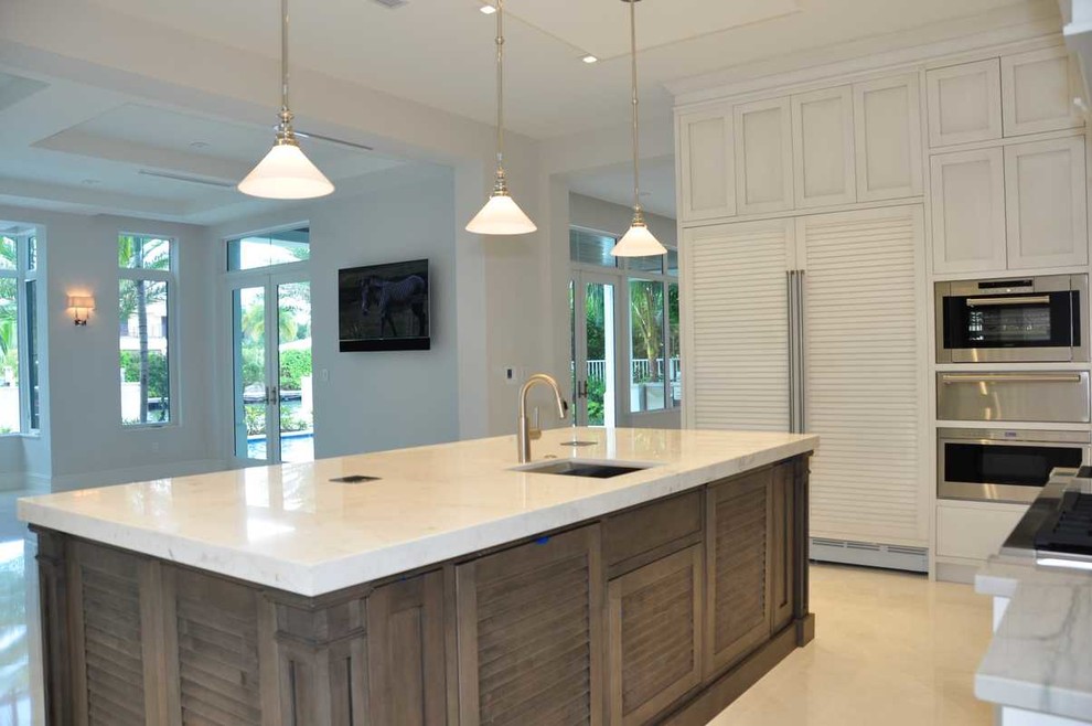 Inspiration for a mid-sized tropical l-shaped open plan kitchen in Miami with an undermount sink, louvered cabinets, white cabinets, marble benchtops, stainless steel appliances, porcelain floors, with island and beige floor.