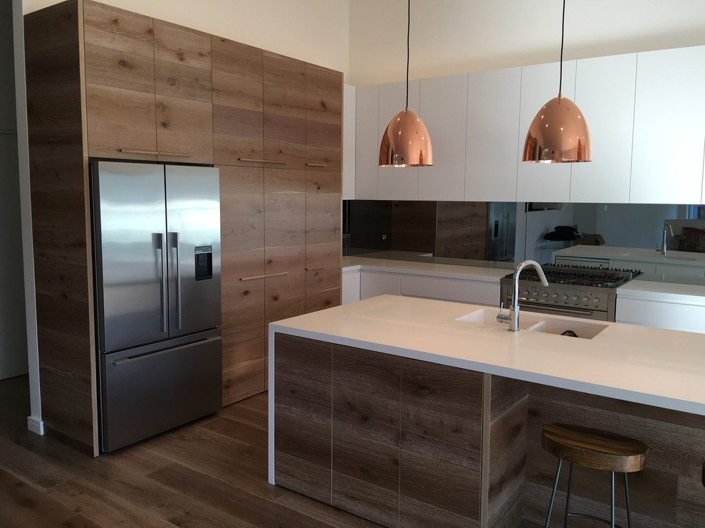 This is an example of a large contemporary galley kitchen pantry in Sydney with a double-bowl sink, medium wood cabinets, quartz benchtops, mirror splashback, stainless steel appliances and with island.