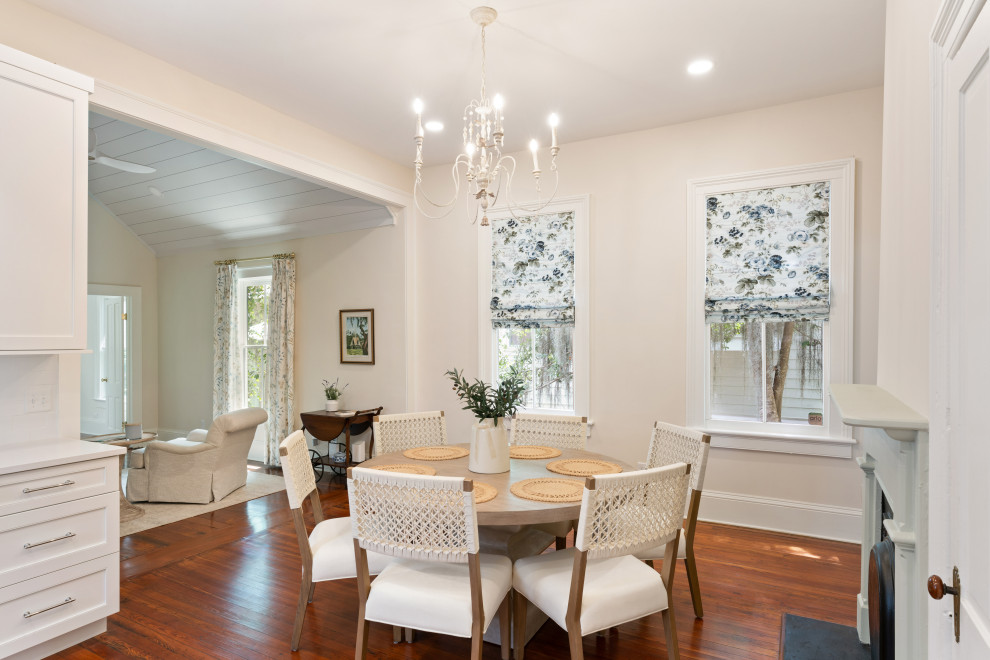 Photo of a small traditional kitchen/dining room in Atlanta with white walls, medium hardwood flooring, a standard fireplace, a wooden fireplace surround, brown floors and a vaulted ceiling.